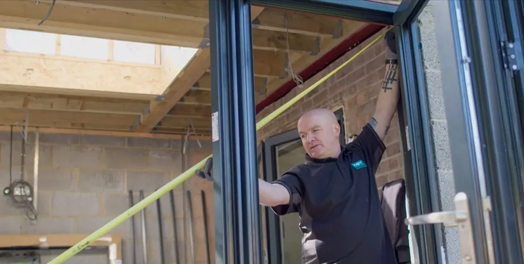20240228-Screenshot 2024-02-28 131618 Measuring a door frame with a tape measure, ensuring it's plumb and level.