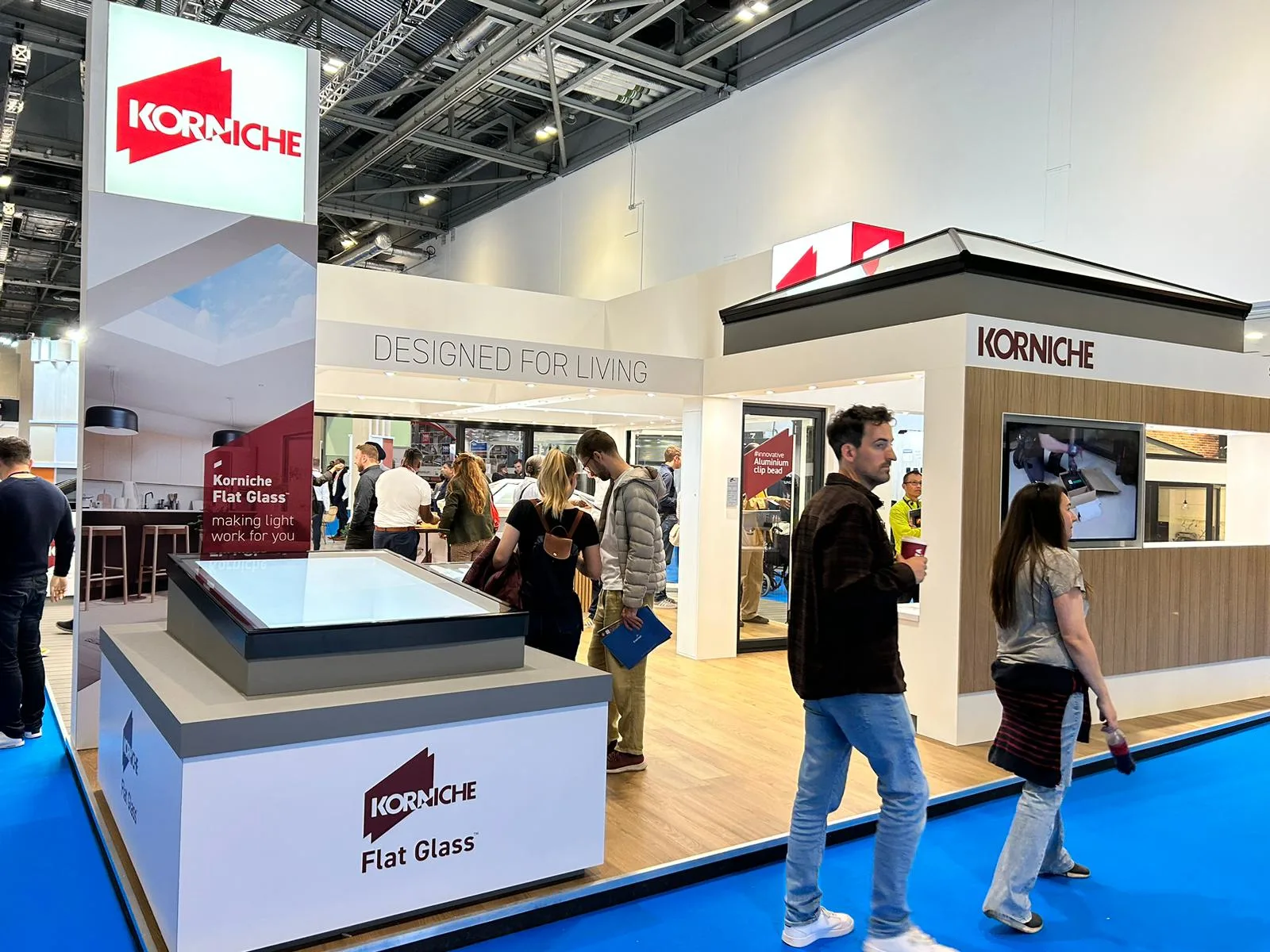 Attendees gathered around the Korniche stand, viewing product displays and interacting with company representatives.