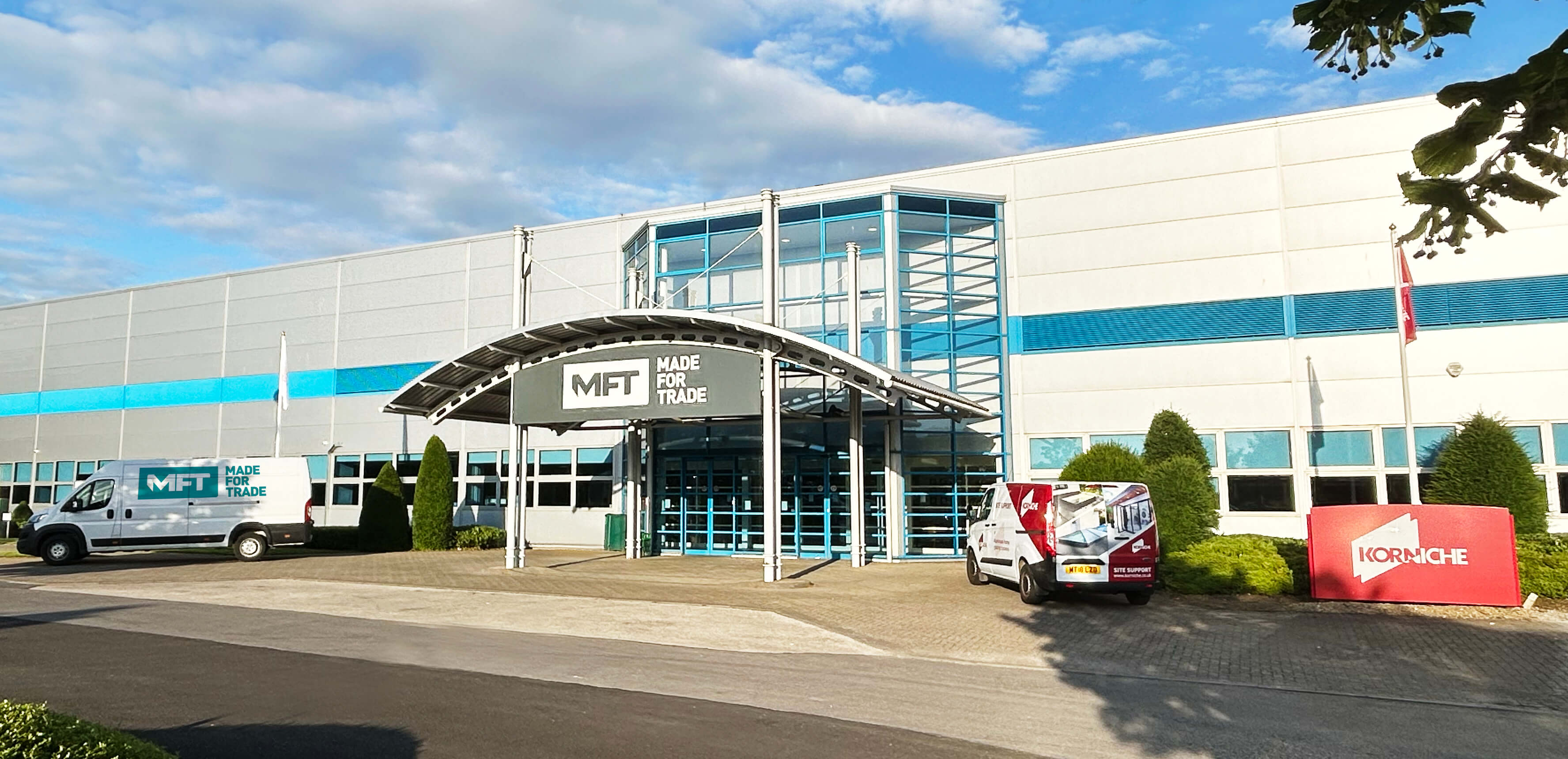 Made For Trade building on a sunny day with blue sky, featuring Made For Trade and Korniche signage and vehicles.