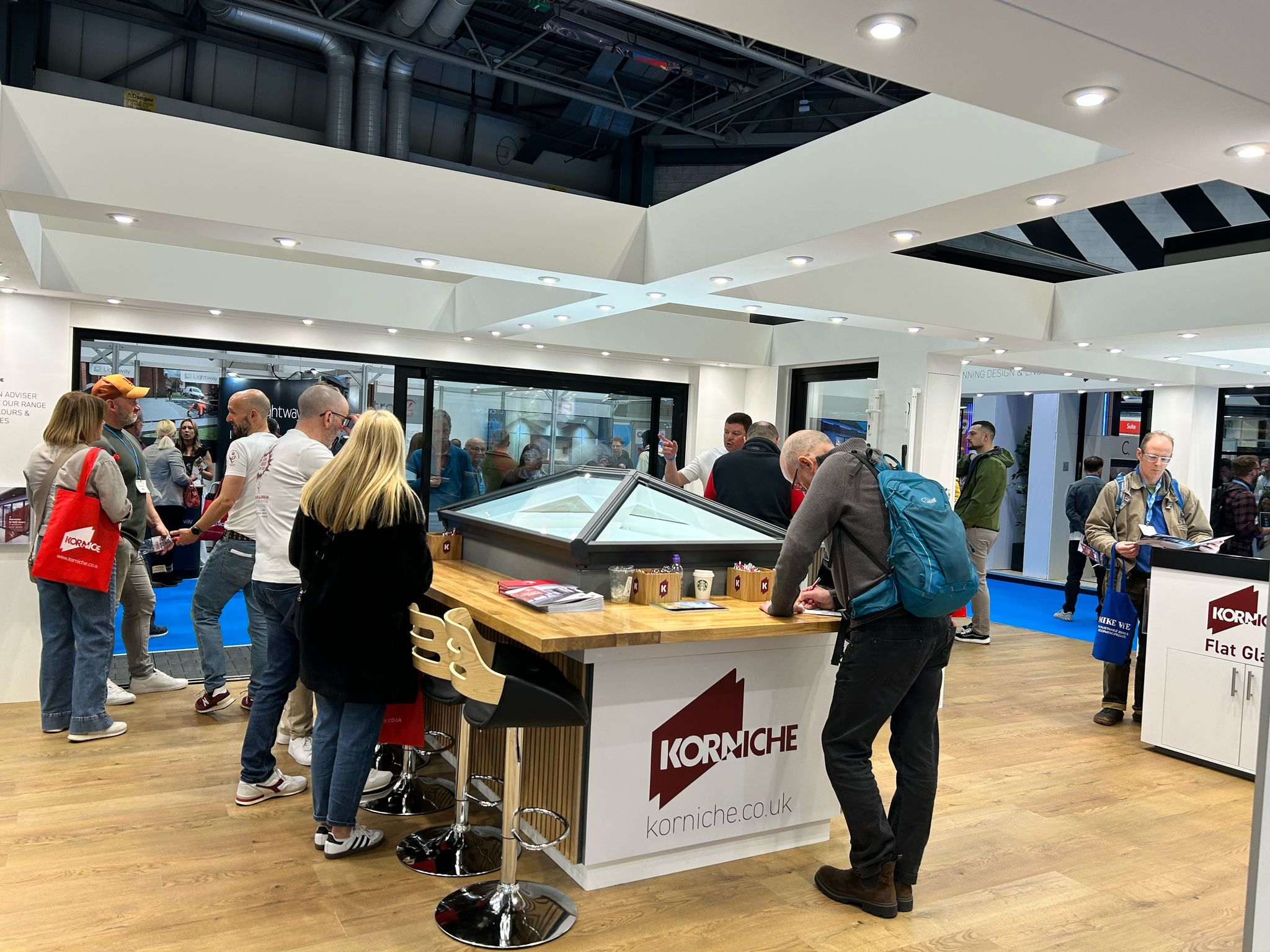Korniche Roof Lantern, Cortizo 4700 Sliding Patio Door, and single glass door on display. Leigh Greenwood, Chris Wann, and Mike Robinson speaking with visitors.