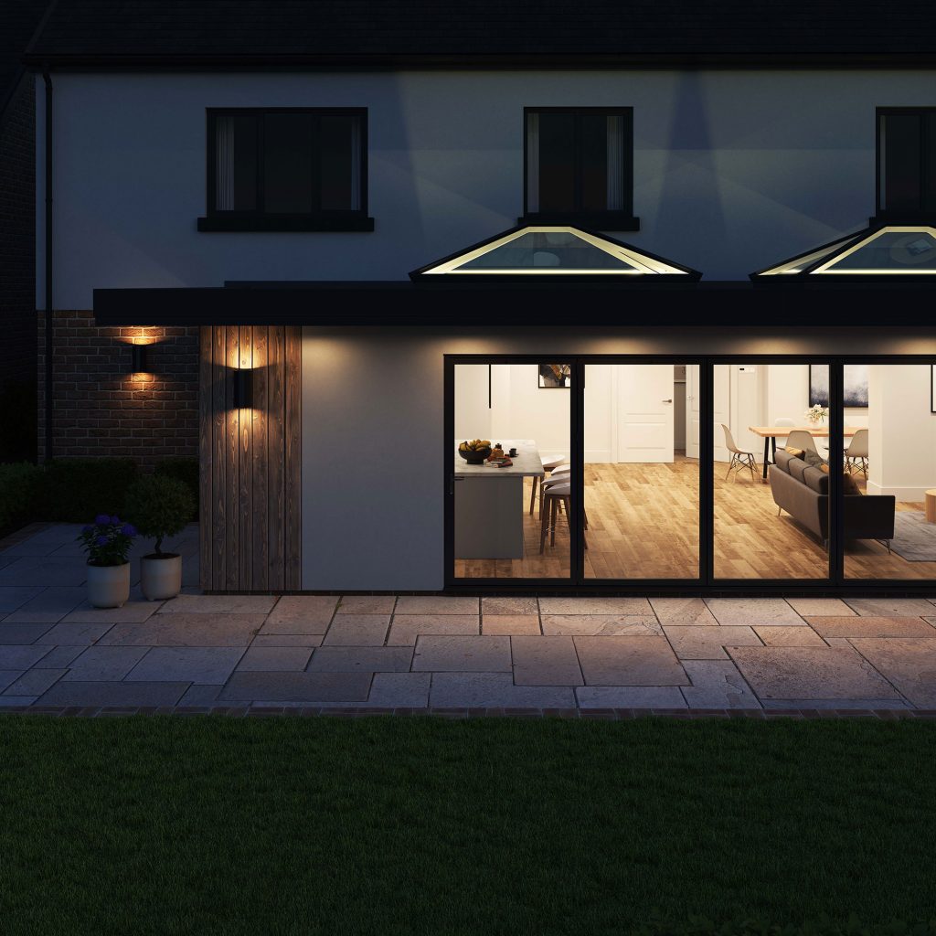 Exterior view at night showcasing two Korniche Roof Lanterns with internal lighting creating an uplighting effect on their architectural structure.