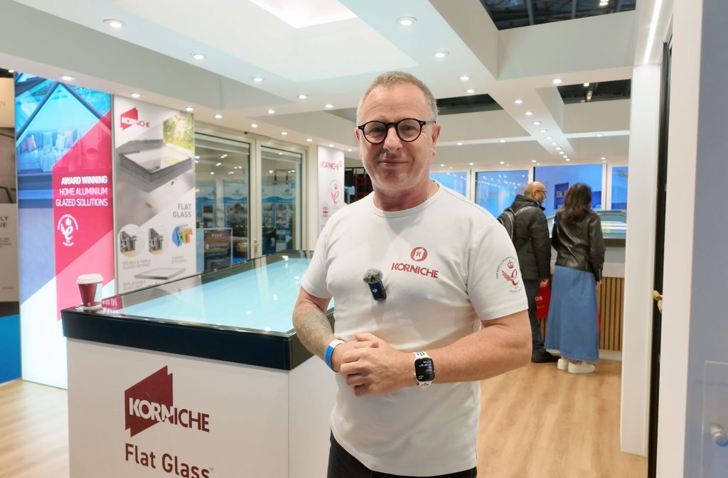 Mark Millar from TV on the Korniche Stand at the London Homebuilding & Renovating Show 2025, standing next to a Korniche Flat Glass Rooflight.